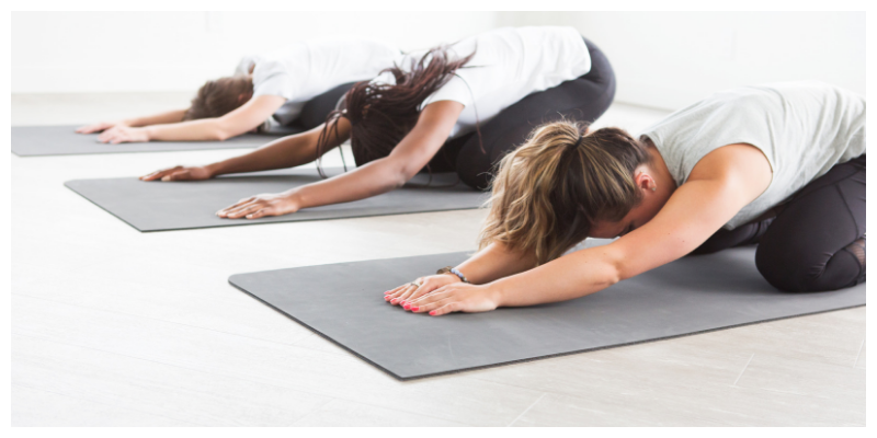 Three women doing yoga in relaxed pose, to relieve menopausal fatigue naturally.