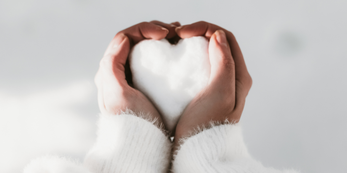 hands holding a heart shaped snowball