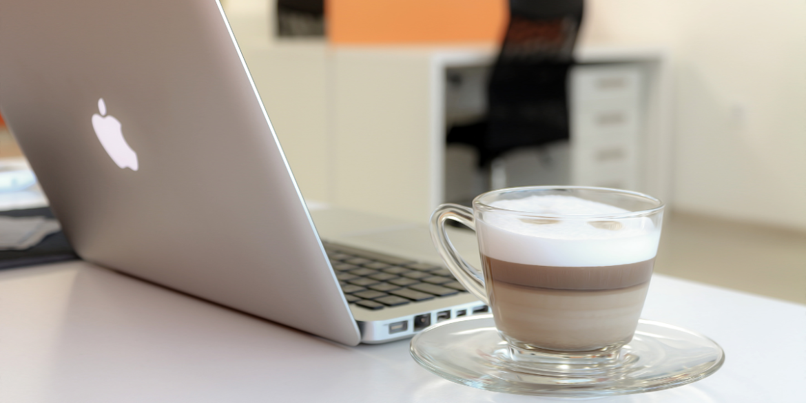 Apple MacBook Pro , open next to a cafe latte